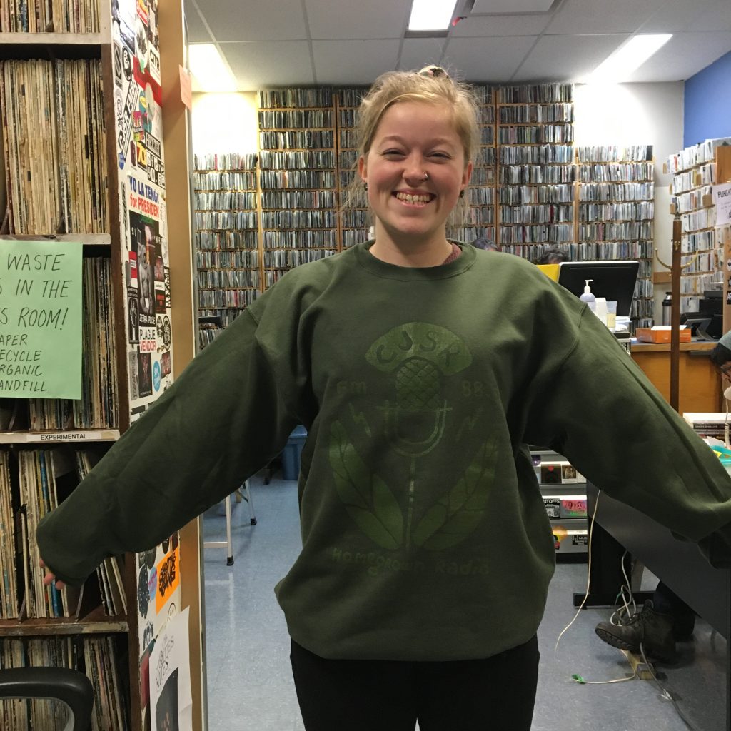 A CJSR volunteer shows off the 2019 Homegrown Radio sweater