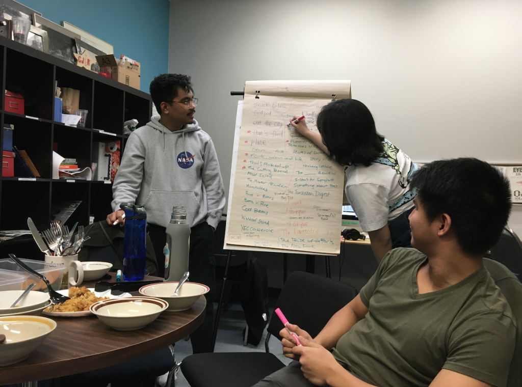 Dan, Sophia, and Ralph looking at a sheet of flipchart paper