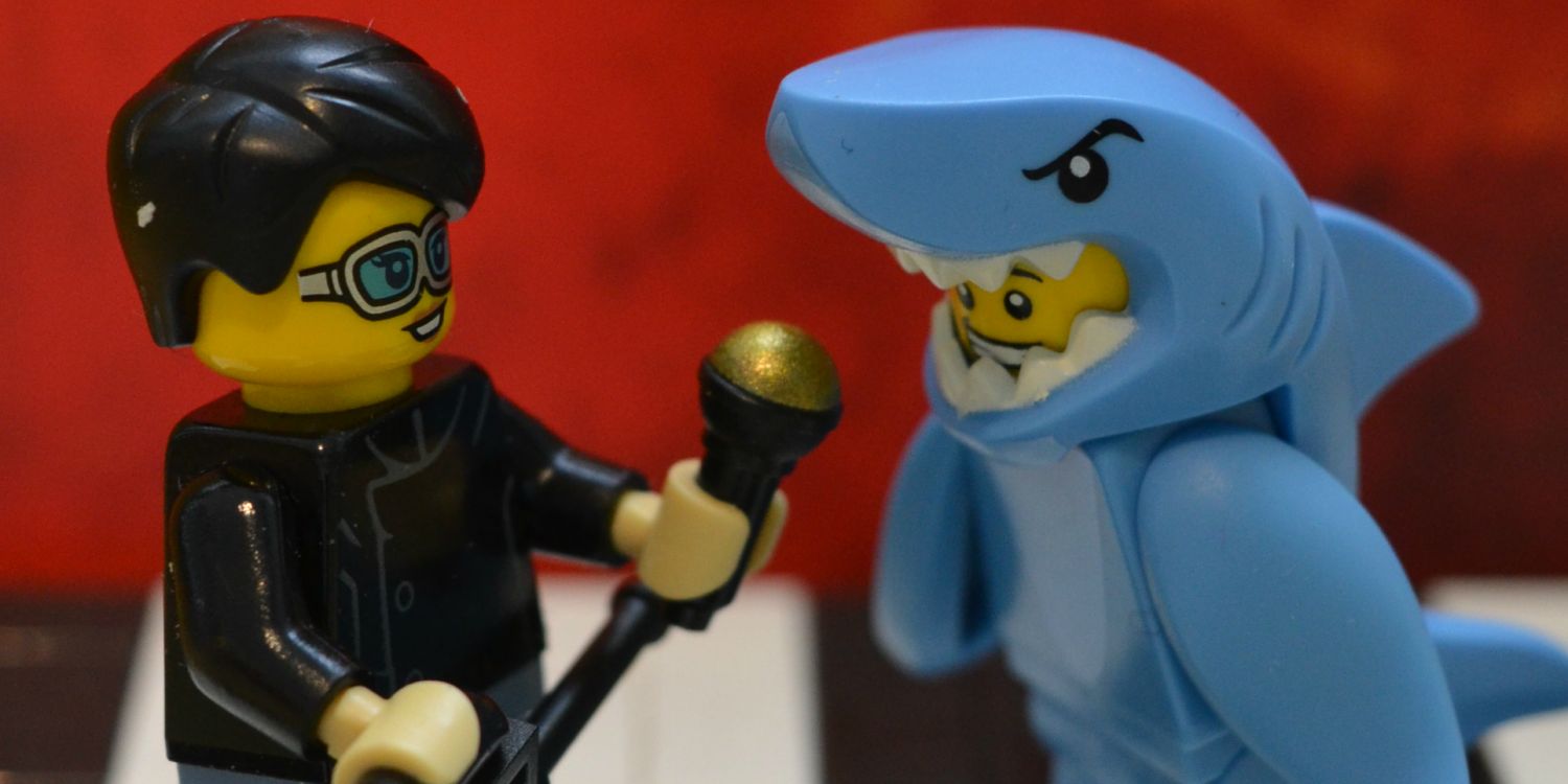 A Lego interviewer holds up a microphone to a Lego man dressed as a shark.