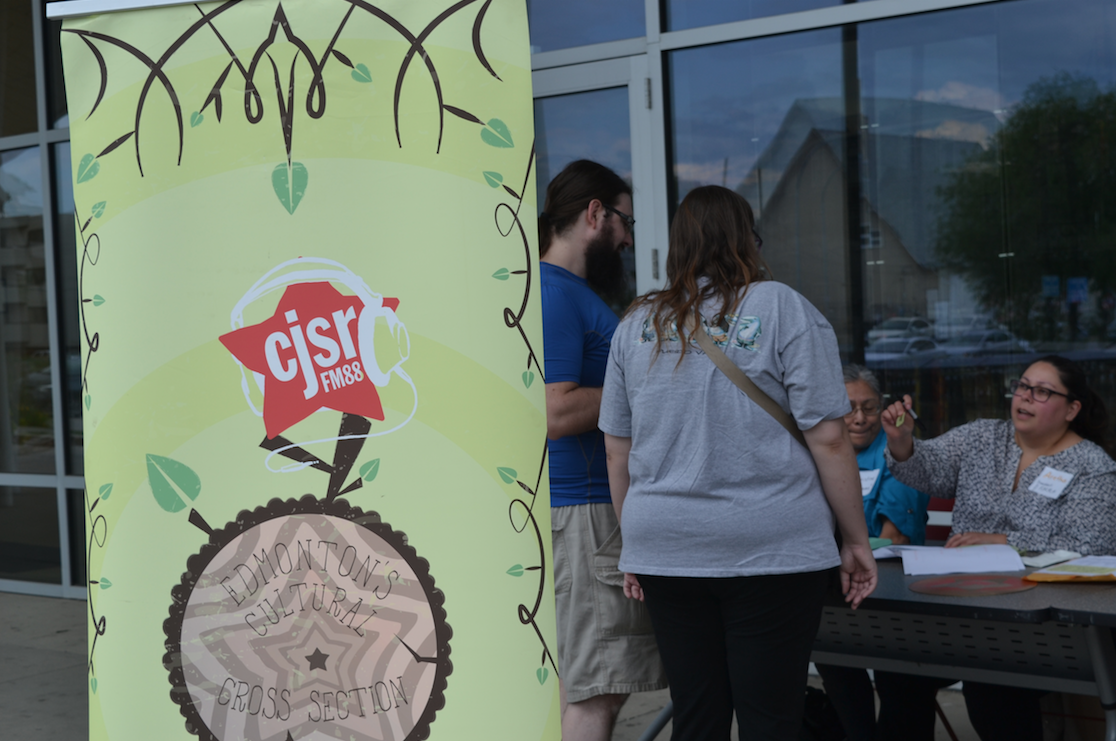 CJSR Banner in front of volunteers at a table